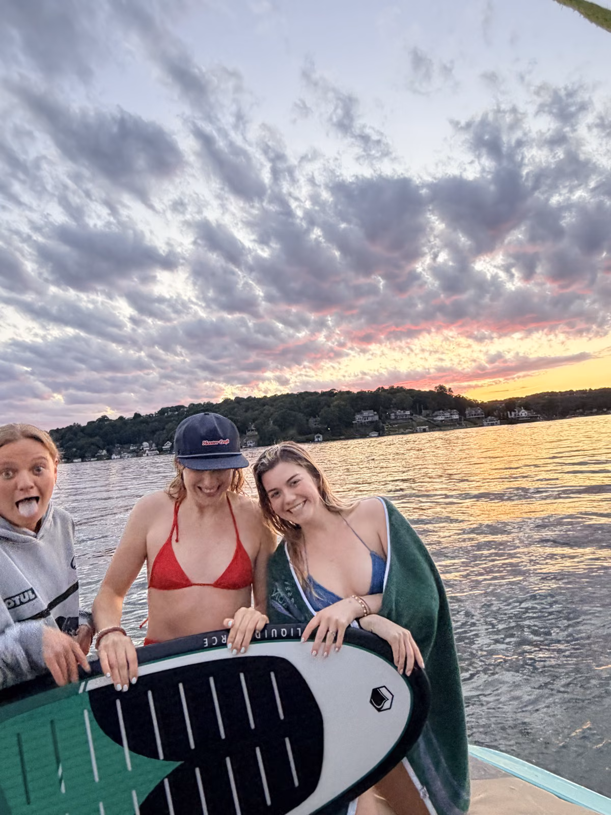 Wake Club guests with a wakesurf board at sunset on Lake Hopatcong